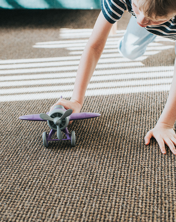 Child playing with toy on durable carpet