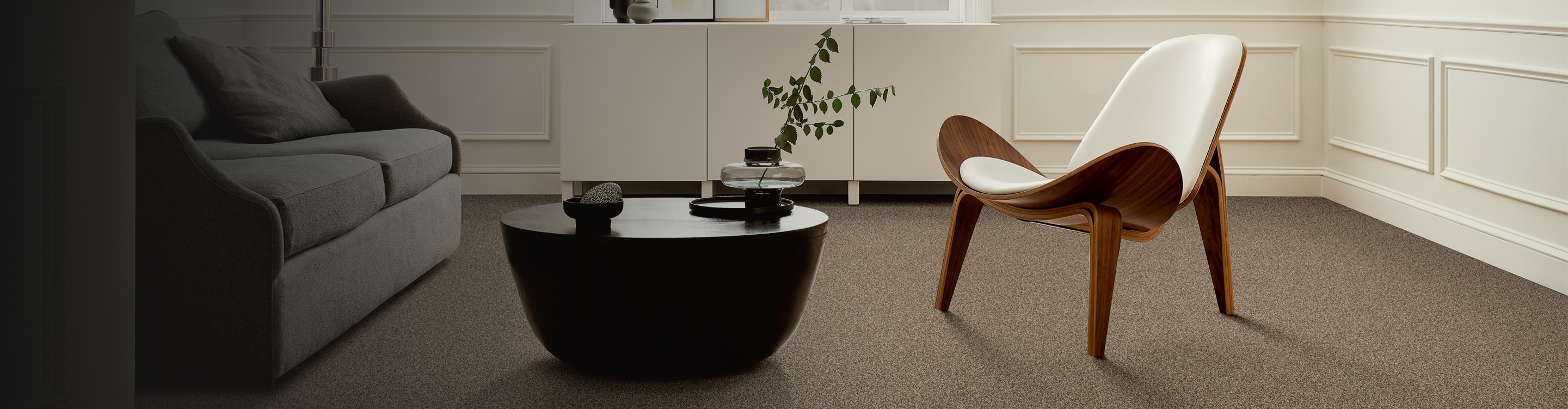 beige carpet in modern living room with black coffee table, white chair and abstract art